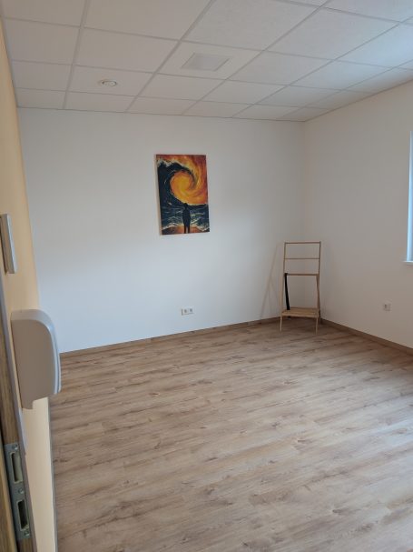 Leerer Raum mit Holzfußboden und einem Wandbild im Hintergrund.
